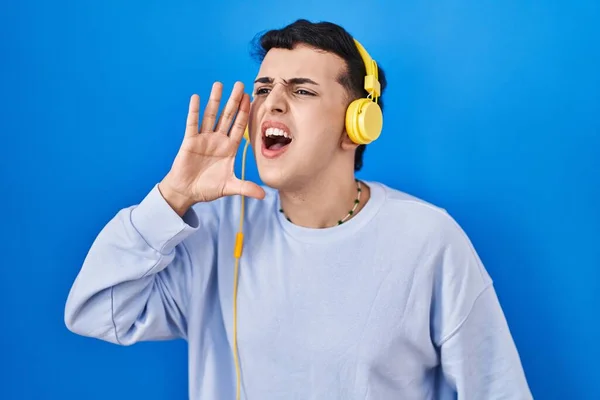 ヘッドフォンの叫びを使用して音楽を聞いている非バイナリの人と口の上に手で大声で叫ぶ コミュニケーションの概念 — ストック写真