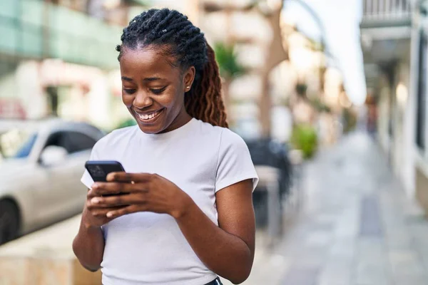 アフリカ系アメリカ人の女性が路上でスマートフォンを使って笑顔で — ストック写真