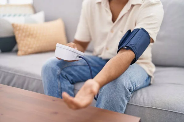 stock image Young arab man using tensiometer sitting on sofa at home