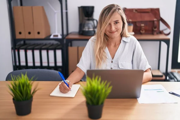 若いブロンドの女性のビジネスワーカーを使用してノートパソコンの文書上の書き込みでオフィス — ストック写真