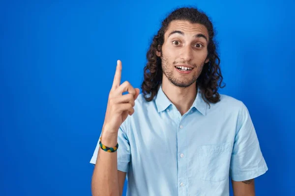 Mladý Hispánec Stojící Nad Modrým Pozadím Ukazující Prstem Nahoru Úspěšným — Stock fotografie
