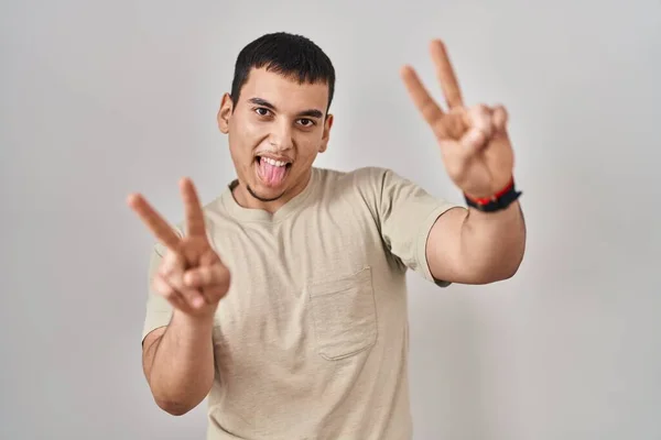 Młody Arabski Mężczyzna Luźnej Koszuli Uśmiechnięty Językiem Pokazujący Palce Obu — Zdjęcie stockowe