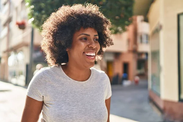 Afro-Amerikalı kadın gülümsüyor. Kendinden emin bir şekilde caddeye bakıyor.