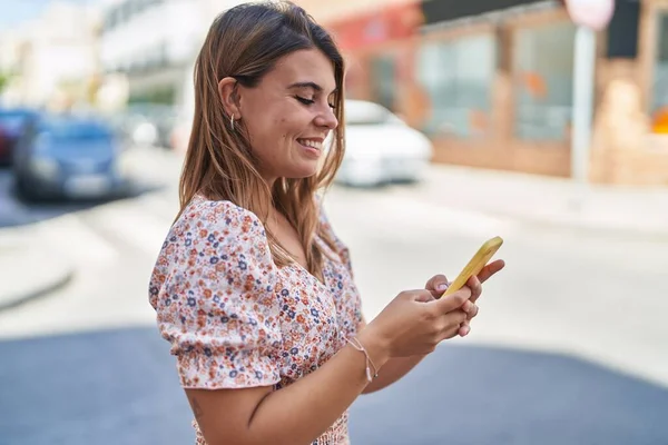 年轻女子自信地微笑着 在街上用智能手机 — 图库照片
