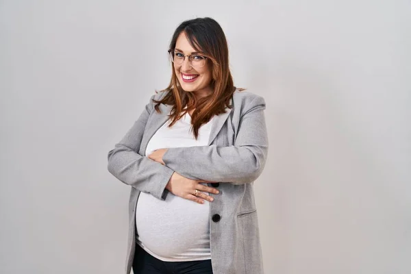 白い背景の上に立つ妊婦さんはカメラを見ながら両腕を組んで笑顔で幸せそうな顔 正の人 — ストック写真