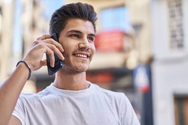 Genç İspanyol adam gülümsüyor. Kendine güveniyor. Sokakta akıllı telefondan konuşuyor.