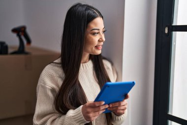 Genç, güzel, İspanyol bir kadın. İş kadını. Ofiste dokunmatik ped kullanıyor.