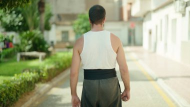 Latin kökenli genç bir karate dövüşçüsü sokakta dikiliyor.