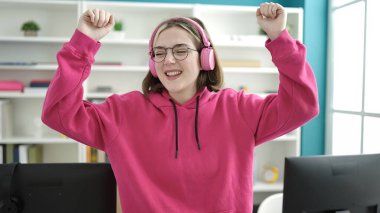 Young blonde woman student smiling confident listening to music and dancing at library university