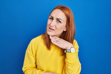 Mavi arka planda dikilen genç bir kadın bıçak gibi boğazını kesiyor, saldırganlığı şiddetle tehdit ediyor. 