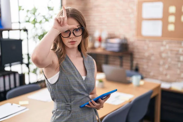 在办公室工作的白人妇女戴着眼镜取笑额头上有手指的人做失败者的手势嘲笑和侮辱 — 图库照片