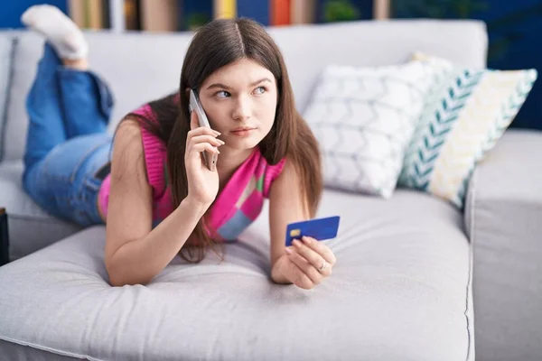 Young Caucasian Woman Talking Smartphone Holding Credit Card Lying Sofa — Stockfoto