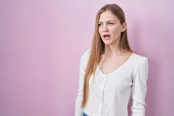 若い白人女性がピンクの背景に立って怒りと怒りで叫んで フラストレーションと激怒叫んで怒っている 怒りと攻撃的な考え方 — ストック写真