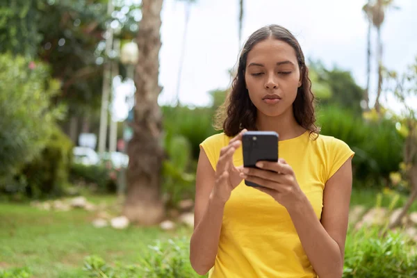 年轻的非洲裔美国女人在公园里用带有严肃表情的智能手机 — 图库照片