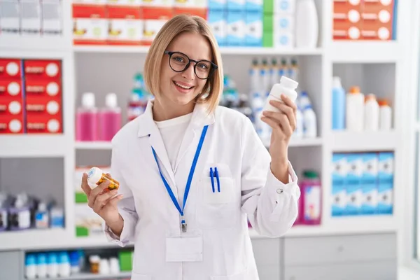 Young Blonde Woman Pharmacist Smiling Confident Holding Pills Bottles Pharmacy — Foto Stock