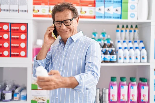 中年男性顧客話して上のスマートフォン保持薬瓶に薬局 — ストック写真