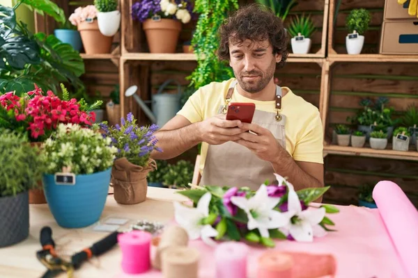 Young hispanic man florist make photo to flowers by smartphone at flower shop