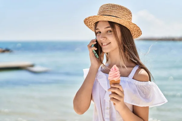 海辺でアイスクリームを食べるスマートフォンで話す愛らしい女の子の観光客 — ストック写真