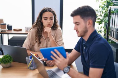 Ofiste çalışan genç İspanyol iş adamları dizüstü bilgisayar ve dokunmatik ped kullanıyorlar.