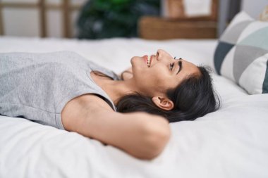 Genç İspanyol kız yatakta kendinden emin bir şekilde gülümsüyor.