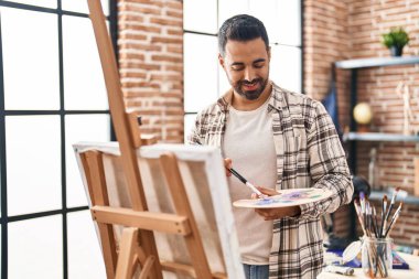 Genç İspanyol adam resim stüdyosunda kendine güvenen gülümsüyor.