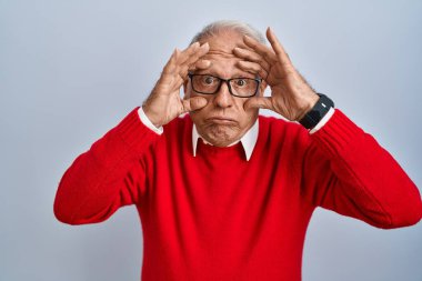 Senior man with grey hair standing over isolated background trying to open eyes with fingers, sleepy and tired for morning fatigue 