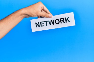 Hand of caucasian man holding paper with network word over isolated blue background