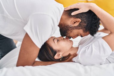 Man and woman couple lying on bed kissing at bedroom