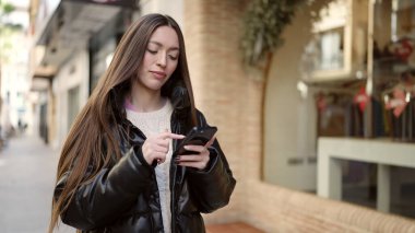 Genç ve güzel İspanyol kadın akıllı telefon kullanıyor. Sokakta ciddi bir ifadesi var.