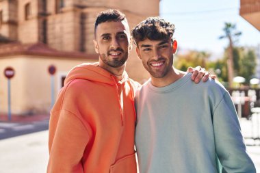 İki erkek caddede birbirlerine sarılıyorlar.