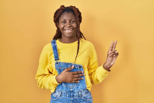 Afrikaanse Vrouw Staat Gele Achtergrond Glimlachend Vloeken Met Hand Borst — Stockfoto