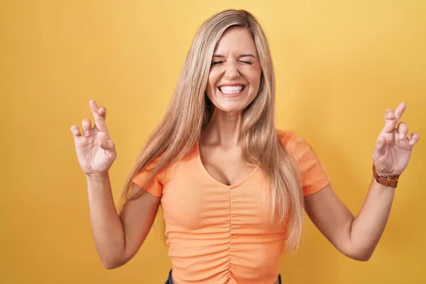 Jonge Vrouw Staat Gele Achtergrond Gebaren Vinger Gekruist Glimlachen Met — Stockfoto