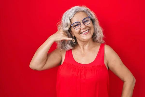 Kırmızı Arka Planda Gri Saçlı Orta Yaşlı Bir Kadın Telefonla — Stok fotoğraf