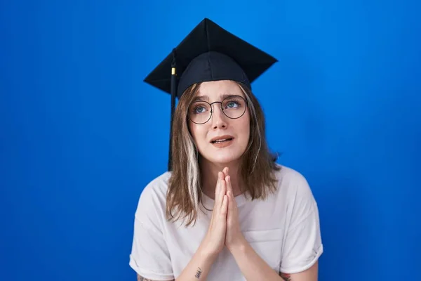 金发高加索女人戴着毕业典礼帽 手牵着手祈求和祈祷 脸上带着希望的表情 非常情绪化和忧虑 — 图库照片