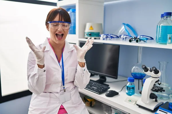 腕を上げて成功のために狂気と狂気を祝う科学研究所で働く若いブルネットの女性は興奮して叫んで目を閉じて叫んだ 勝者のコンセプト — ストック写真