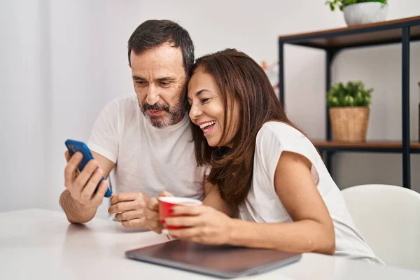 中年男人和女人坐在家里的桌子上 用智能手机喝咖啡 — 图库照片