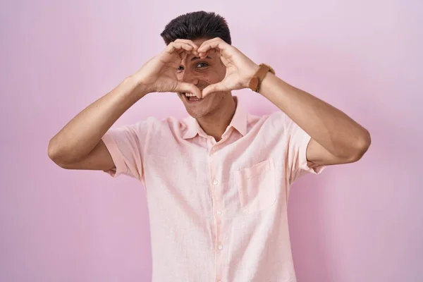 Mladý Hispánec Muž Stojící Nad Růžovým Pozadím Dělá Srdce Tvar — Stock fotografie