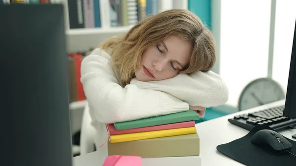 年轻的金发女学生靠在图书馆的书本上睡觉 — 图库照片