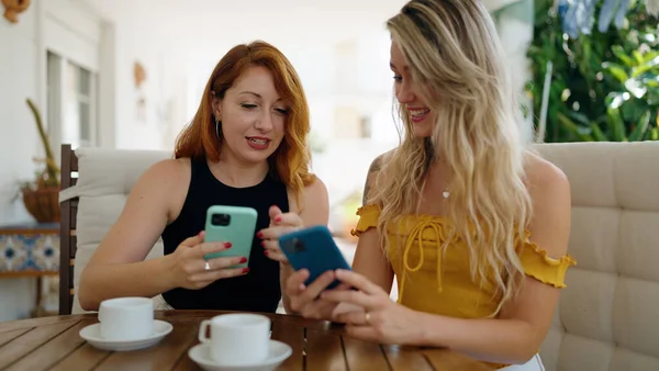 Δύο Γυναίκες Που Χρησιμοποιούν Smartphones Και Πίνοντας Καφέ Κάθονται Στο — Φωτογραφία Αρχείου