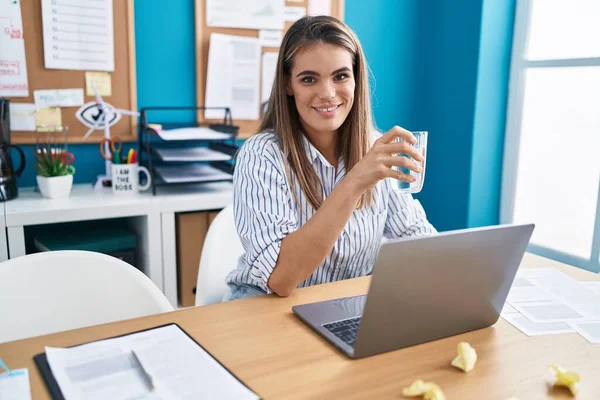 在办公室用笔记本电脑喝水的年轻漂亮的惊慌失措的女商人 — 图库照片