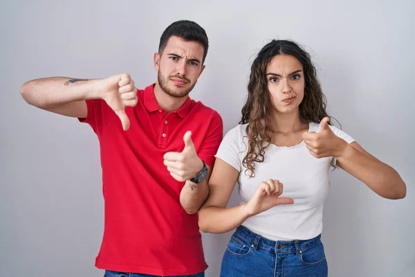 Young Hispanic Couple Standing Isolated Background Doing Thumbs Disagreement Agreement — Stock Photo, Image