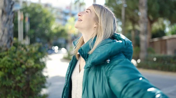 Young blonde woman smiling happy with open arms at park