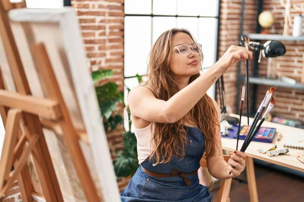Young Beautiful Hispanic Woman Artist Holding Paintbrushes Art Studio — Stock Photo, Image