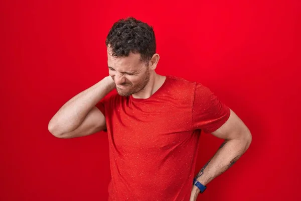 Young Hispanic Man Standing Red Background Suffering Neck Ache Injury — Stockfoto