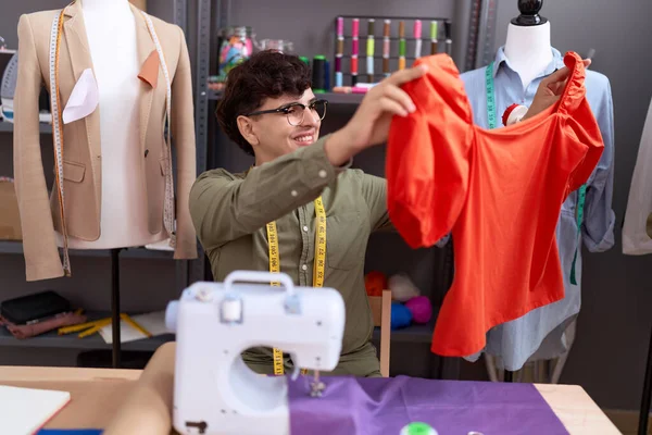 Non binary man tailor smiling confident holding t shirt at atelier