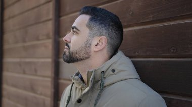 Latin kökenli genç adam ciddi bir ifadeyle sokağa bakıyor.