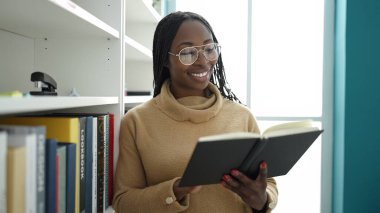 African woman reading a book at library university