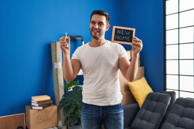 Sakallı, elinde yeni evin anahtarları olan genç İspanyol adam kameraya seksi bir ifadeyle bakıyor, neşeli ve mutlu bir yüzle.. 