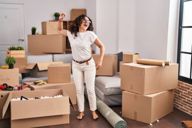 Middle age hispanic woman dancing at new home