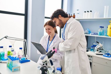 Erkek ve kadın bilim adamları laboratuarda çalışıyor.